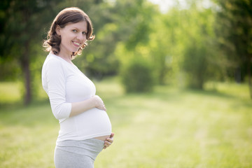 Fototapeta premium Happy pregnant woman on late pregnancy stage posing in park