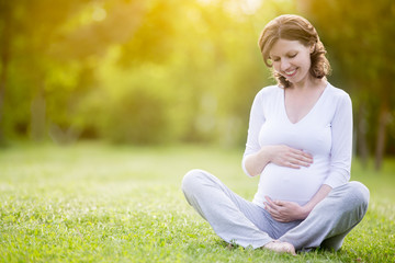 Smiling future mom holding her belly with tender smile