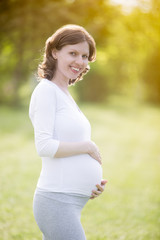 Happy pregnant woman on late pregnancy period walking in park