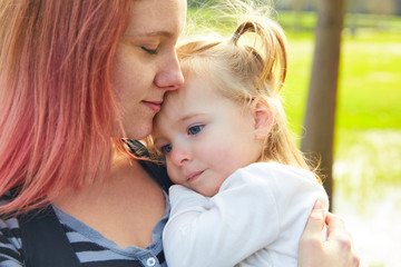 Mother and daughter portrait hug kissing in park