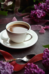 Beautiful background with a Cup of hot coffee with lilacs