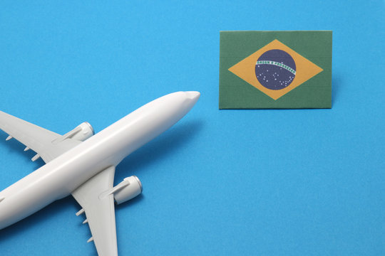 Miniature airplane flies toward Brazil flag.
