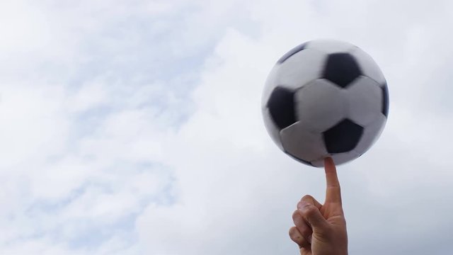 4K Football or soccer ball spinning on a finger against a sky background, with space for text