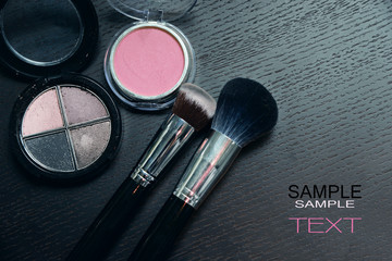 Makeup cosmetics products on wooden black background