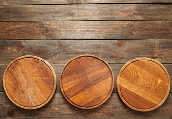 Op de houten tafel onderaan de foto liggen drie lege houten pizzaborden. Ruimte kopiëren. Horizontale lijn. Plat leggen van lege houten pizzaborden