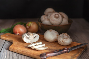 Sliced mushrooms closeup, lying on wooden cutting board with knife.
