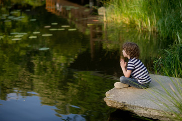 Little boy sits cross-legged on the lake.