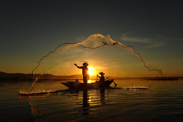 Fisherman of asian people at Lake in action when fishing during sunrise - obrazy, fototapety, plakaty