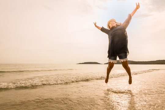 Happy young woman jumping on beach (tone color photo)