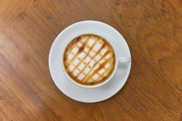 Hot caramel macchiato on wooden table.