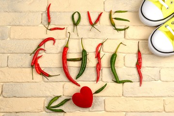 Love inscription from red chili peppers on a brick background