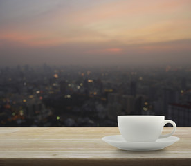 White cup on wooden over blurred aerial view of cityscape on war