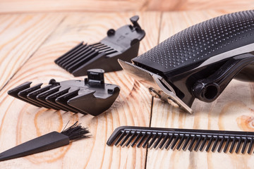 Obraz premium hair trimmer with attachment and a comb on wooden background
