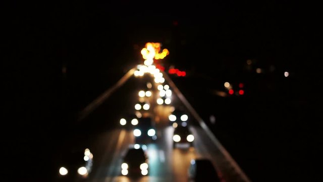 Defocused lights of heavy city traffic, long line of cars leaving city at night
