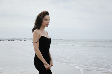 jolie femme brune en robe noire à la mer