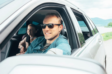 Father and son look out from car window