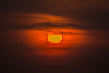 Summer sunset. The setting sun in a cloudy sky background.