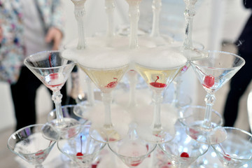 Beautiful wedding slide champagne for bride and groom indoors. Colorful glasses for alcohol with berries. Beauty of bridal interior for marriage. Bright bar for celebration