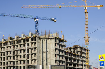 Two construction cranes over the cast-concrete building