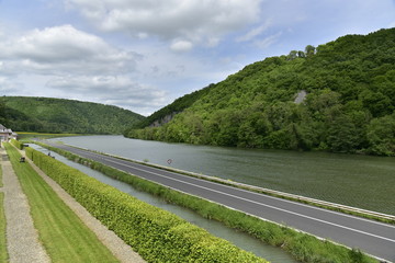 La route longeant la Meuse et le canal séparant les jardins majestueux du château de Freyr dans un paysage verdoyant à Hastière
