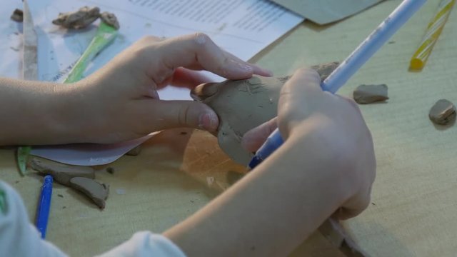 Kid is Cutting Out Shapes a Dolphin Clay Figurine Working Attentively at the Messy Table Child is Learing a Pottery Craft at Pottery Workshop