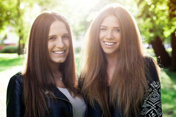 Close up two young smiling women in the city park