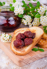 Toast with strawberry jam on wooden board on wooden background. Selective focus
