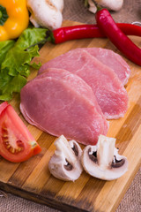 Raw pork on cutting board and vegetables