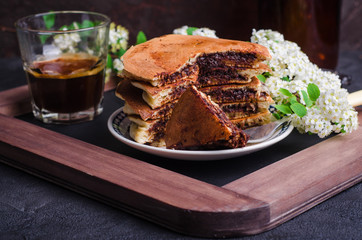 Stuffed chocolate pancakes on n vintage slate chalk board background with flowers and coffee cup. Selective focus