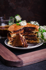 Stuffed chocolate pancakes on n vintage slate chalk board background with flowers and coffee cup. Selective focus