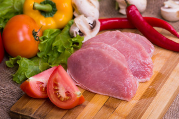 Raw pork on cutting board and vegetables