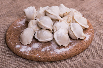 Fototapeta na wymiar Uncooked dumplings Pelmeni. Traditional Russian dish. Background from pelmeni laid out on a chopping board
