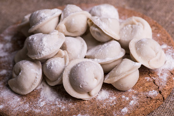 Uncooked dumplings Pelmeni. Traditional Russian dish. Background from pelmeni laid out on a chopping board
