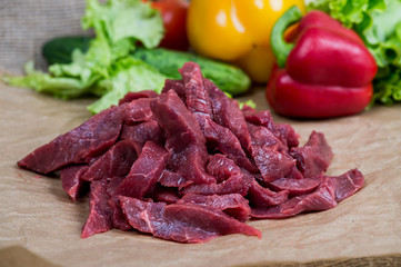 Fresh raw chopped beef, spices and herbs on a light wooden background