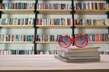 sun glass on book stack and book shelf background