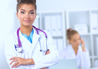 Fototapeta premium Portrait of young woman doctor with white coat standing in hospital