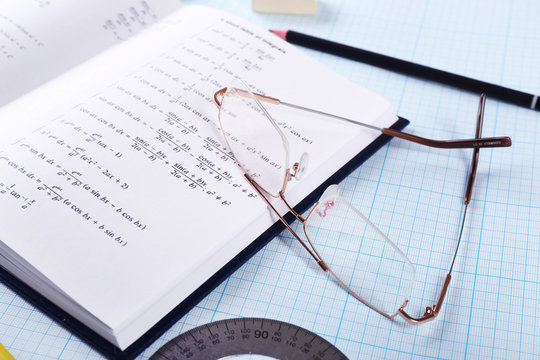 School supplies and textbook on mathematics close up