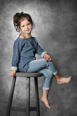 Portrait of little fashion kid girl on gray wall background