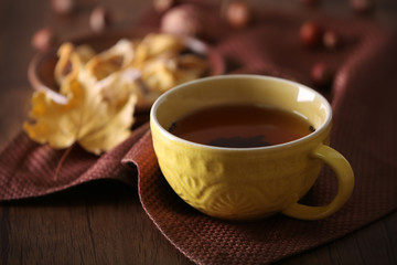 Cup of tea with autumn decor on wooden table.
