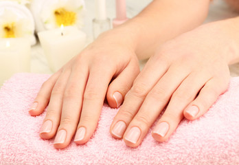 Spa concept. Woman hands with beautiful manicure and flowers on towel, close up