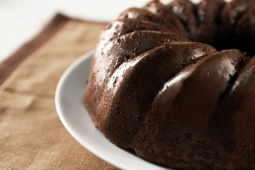 Chocolate cake on plate on white wooden background