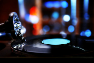 Turntable with vinyl record on dark blurred background