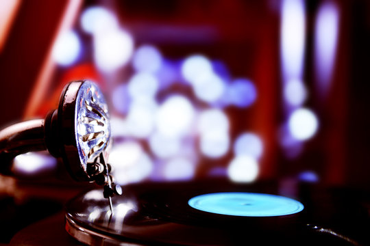 Turntable with vinyl record on dark blurred background