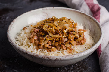 Mujadarra - arabian dish with rice, lentils and onion on dark  background. Ramadan food. Eastern cuisine. Selective focus