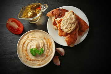 Ceramic bowl of tasty hummus with parsley on table