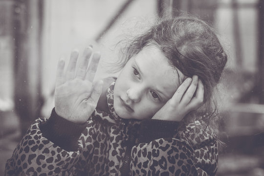 Sad girl looking from the window. Black and white portrait.