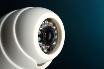 Security CCTV camera on blue background, closeup