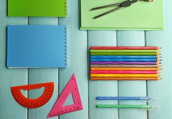 School set with notebooks, divider and colored pencils on wooden blue background