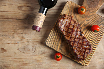 Grilled steak on cutting board with wine and cherry tomatoes, closeup