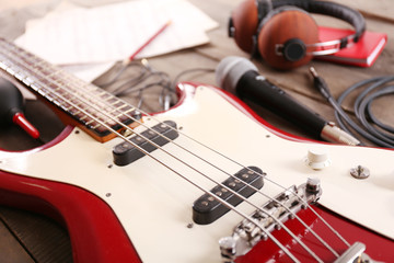 Fototapeta premium Electric guitar with notes, microphone and headphones on wooden background